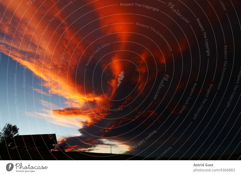 Gewitterwolken bei Sonnenuntergang über einem Haus sonnenuntergang abendrot himmel regenwolken abendhimmel wiese feld blau land landschaft stromkabel sommer