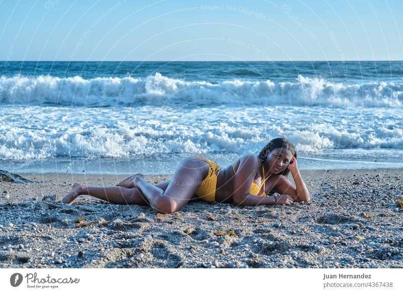 Afroamerikanische Frau liegt auf dem Sand am Strand mit Meereswellen im Hintergrund Afrikanisch Amerikaner Lügen MEER Wellen Afro-Look sich[Akk] entspannen