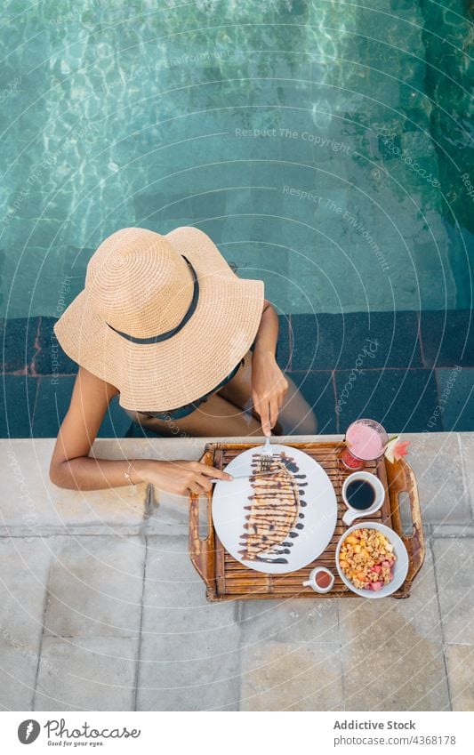 Unerkannter Reisender im Pool, der beim Frühstück im Freien Crepes schneidet Tourist geschnitten Crêpe Kraftschale Resort lecker süß Frau Kaffee Urlaub Messer