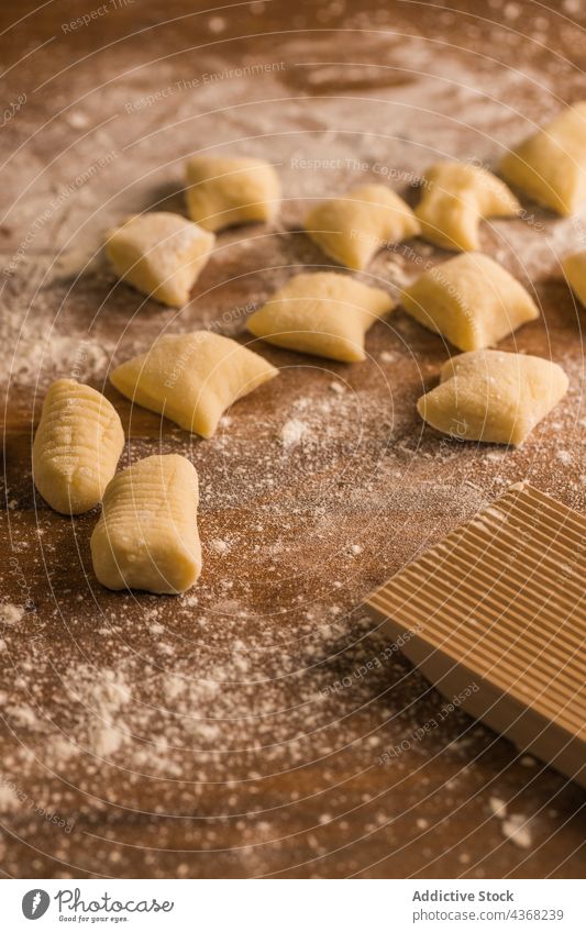 Rohe Teigstücke neben dem Rippenbrett Gnocchi Teigwaren roh Koch Tisch Holzplatte gerippt Mehl Bestandteil Küche vorbereiten Lebensmittel frisch Spätzle