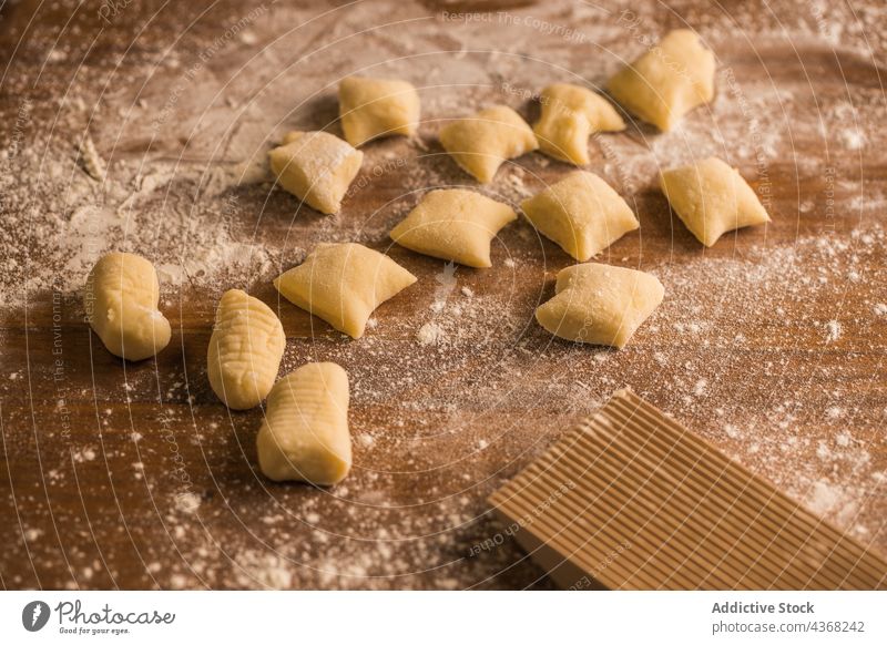 Rohe Teigstücke neben dem Rippenbrett Gnocchi Teigwaren roh Koch Tisch Holzplatte gerippt Mehl Bestandteil Küche vorbereiten Lebensmittel frisch Spätzle