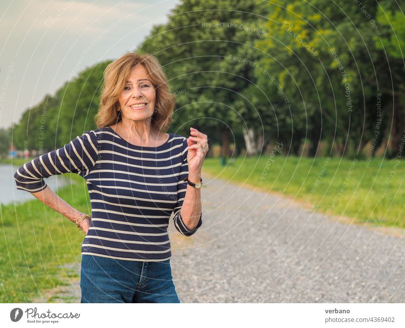 fitte ältere Frau entspannt sich in der Natur am See reif Glück Wellness Kaukasier Körpersprache gesund Lächeln Porträt schön Schönheit Lifestyle Pflege Haut