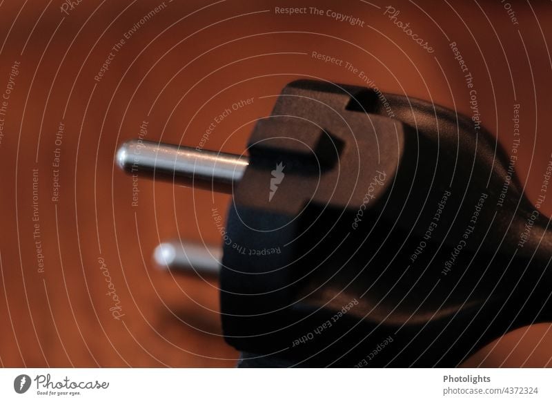 Schwarzer Schuko Stecker / Netzstecker auf braunem Hintergrund schwarz Schukostecker elektrisch Unschärfe Elektrizität Technik & Technologie Steckdose Anschluss