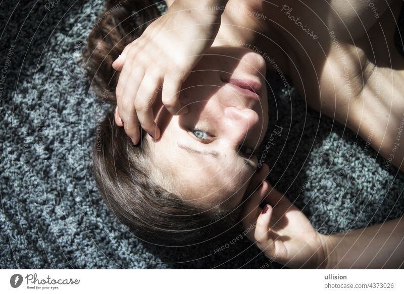 Portrait einer schönen jungen attraktiven sexy Frau, auf Teppich liegend, teilweise mit Schatten eines Fadenvorhangs Lügen Porträt dekorativ Schnur Gardine