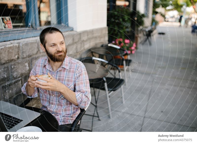 Junger Mann arbeitet aus der Ferne in einem Café im Freien 25-30 30-35 Jahre Erwachsener Amerikaner Vollbart bärtig Blogger Chef brünett Geschäftsinhaber