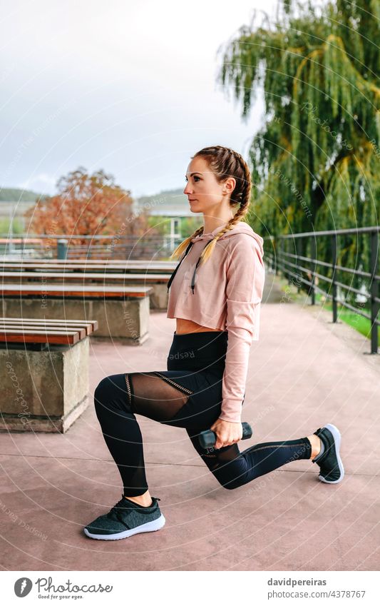 Junge Frau Training mit Hanteln Sportlerin Ausfallschritt Kurzhantel Fitness strecken geduckt Beine Aufwärmen Übung Kraft jung Boxerflechten Gesundheit Mädchen