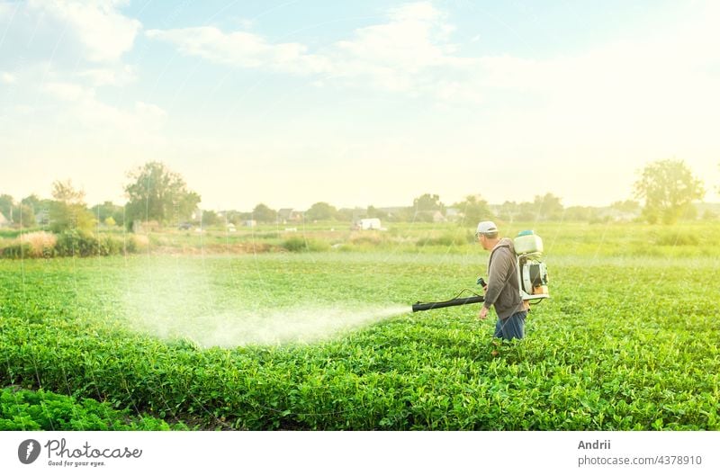 Ein Landwirt geht mit einem Sprühgerät durch eine Kartoffelplantage. Einsatz von Chemikalien in der Landwirtschaft. Landwirtschaft und Agroindustrie. Behandlung des Ackers gegen Schädlinge und Pilzbefall