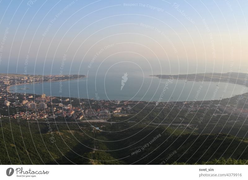 Blick von oben auf die malerische Gelendzhik-Bucht im Abendlicht. Das blaue Schwarze Meer fließt am Abend sanft in den rosa-violetten Himmel. Der Ferienort Gelendzhik.