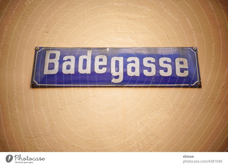 blaues Straßennamenschild  - Badegasse -  an einer hellen Wand / Adresse / Straßenverzeichnis Gasse wohnen Hausmauer Orientierung Schild Straßenbezeichnung