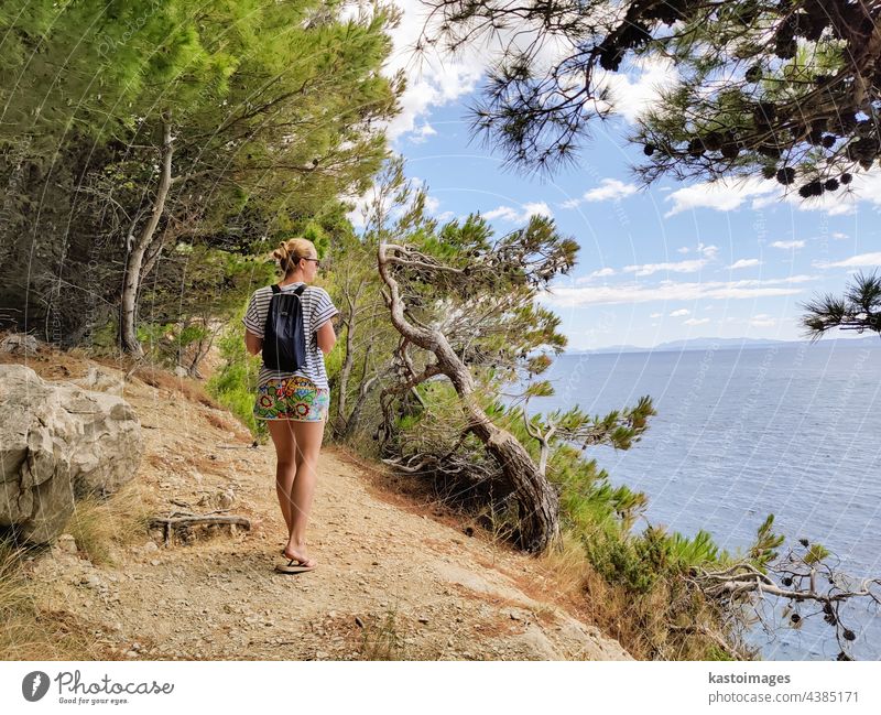 Junge aktive feamle Tourist trägt kleinen Rucksack zu Fuß auf Küstenpfad unter Pinien auf der Suche nach abgelegenen Bucht zu schwimmen allein in Frieden am Meer in Kroatien. Reisen und Abenteuer Konzept