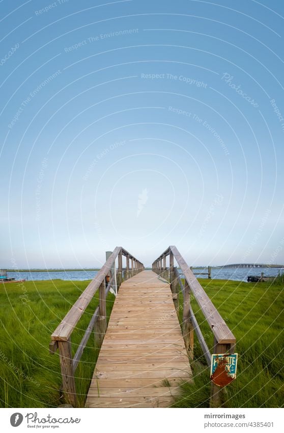 Holzsteg zum Bootssteg und zum Uferbereich Hintergrund Strand schön blau Bootsanleger und Wasserfront Brücke Gras grün Landschaft Natur schönes Tageslicht