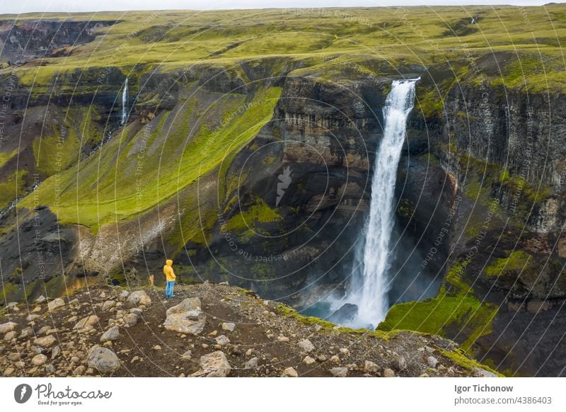 Luftaufnahme eines Mannes, der am Rande einer Klippe steht und das isländische Hochlandtal und den Haifoss-Wasserfall genießt Antenne Landschaft Fluss oben