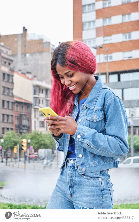 Flippige ethnische Frau mit Smartphone auf der Straße Nachricht Stil gefärbtes Haar Farbe urban informell Hipster jung schwarz Afroamerikaner tausendjährig