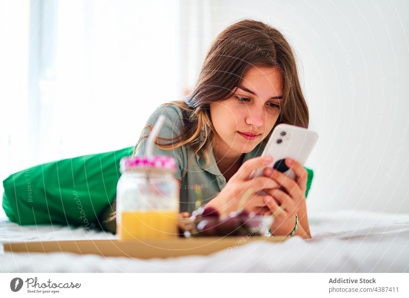 Junge Frau benutzt Smartphone beim Frühstück benutzend zu Hause Morgen online Browsen Internet Kommunizieren jung Schüler Mobile Apparatur Gerät Telefon Surfen