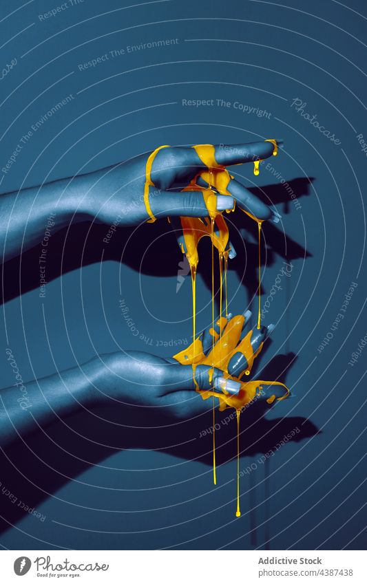 Crop-Modell mit orangefarbenem Farbfluss auf der Hand Farbe Flüssigkeit ultraviolett Körperkunst Kontrast zähflüssig Maniküre Schatten Frau sanft Licht fließen