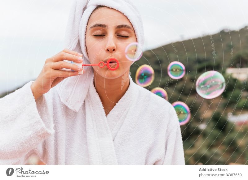 Junge Frau, die während der Hautpflege Seifenblasen bläst Schlag Balkon heimwärts Wochenende ruhen Sauberkeit Spa jung Air Spielzeug spielen Hygiene Terrasse