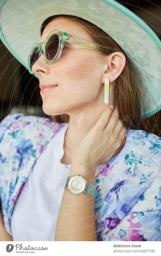 Lächelnde Frau mit Hut vor einem Gebäude mit Backsteinmauer Mode Stil Sonnenbrille freundlich herzlich Stadt Porträt Backsteinwand stylisch anhaben Ornament