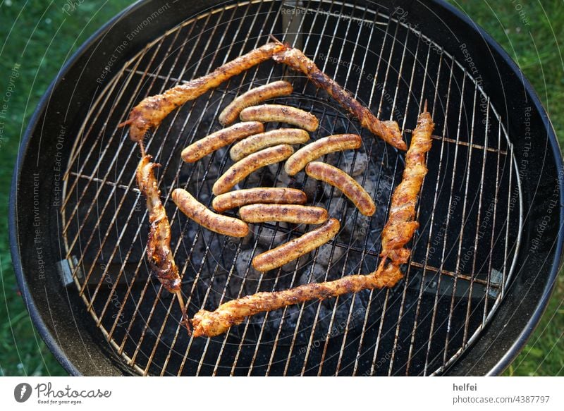 Grillen mit Bratwürste und Fleisch spieße künstlerisch aufgelegt auf dem Kugelgrill Gitter Spieße Grillrost Grillsaison lecker Camping gegrilltes Fleisch