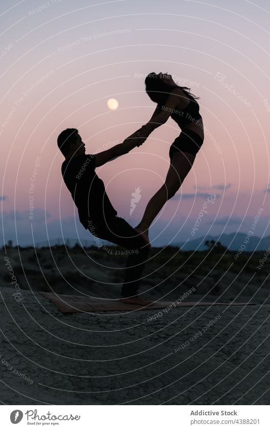 Silhouette von Paar tun acroyoga gegen Sonnenuntergang Himmel Akro-Yoga Gleichgewicht Partner Zusammensein üben akrobatisch Händchenhalten Pose abstützen Abend