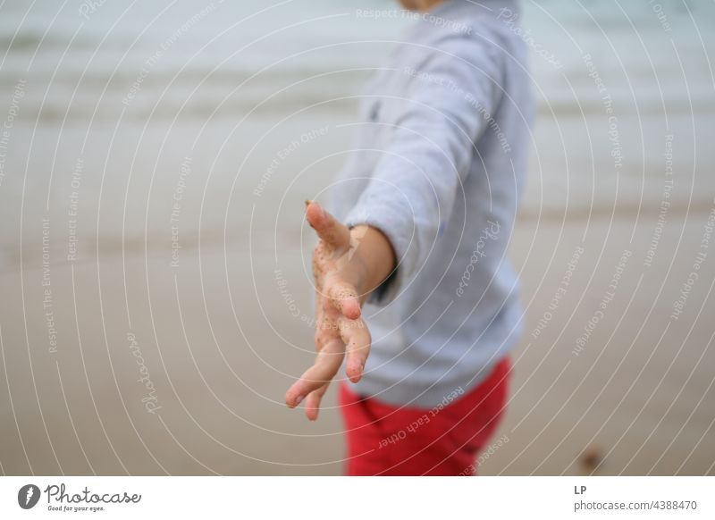 Kind allein am Strand, das einen Arm in Richtung der Kamera zeigt positive Emotion Risiko Sehnsucht einzeln vereinzelt Single abstrakt fließen Kinderspiel