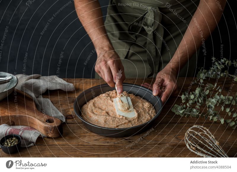 Crop Cook Teig in die Form streichen Mann Koch Pasteten Kürbis Büchse Aufstrich Tisch rustikal Spachtel männlich Dessert Küche Küchenchef Holz Gebäck Speise