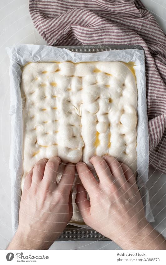 Der Koch bereitet den Teig für die Zubereitung der traditionellen Focaccia vor vorbereiten roh Teigwaren Person Prozess Brot Tradition Backpapier Speise