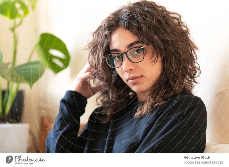 Junge Frau mit Brille ruht sich zu Hause aus krause Haare jung Porträt ruhen Stil tausendjährig ethnisch hispanisch Spektakel Lifestyle Starrer Blick gemütlich