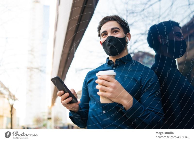 Junger Mann benutzt sein Mobiltelefon im Freien. jung Mobile Telefon urban Gesicht Mundschutz covid-19 Anschluss Schutz Kaffee Porträt Drahtlos Beteiligung