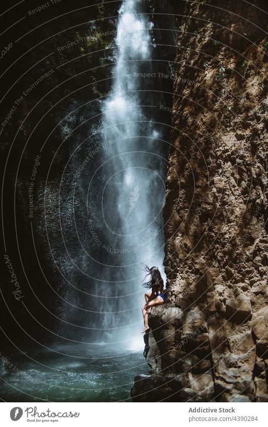 Frau sitzt auf einem Felsen in der Nähe eines Wasserfalls Natur Reisender frisch allein sich[Akk] entspannen platschen ruhen Tourist Urlaub reisen Erholung