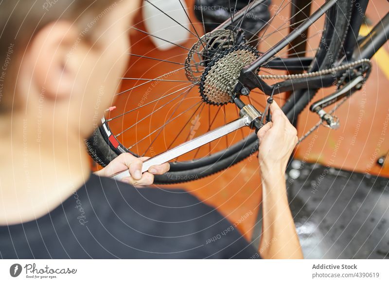 Crop Mechaniker Befestigung Fahrrad Rad mit Steckschlüssel Mann fixieren Werkstatt Schraubenschlüssel Reparatur Dienst männlich Arbeit Gerät professionell