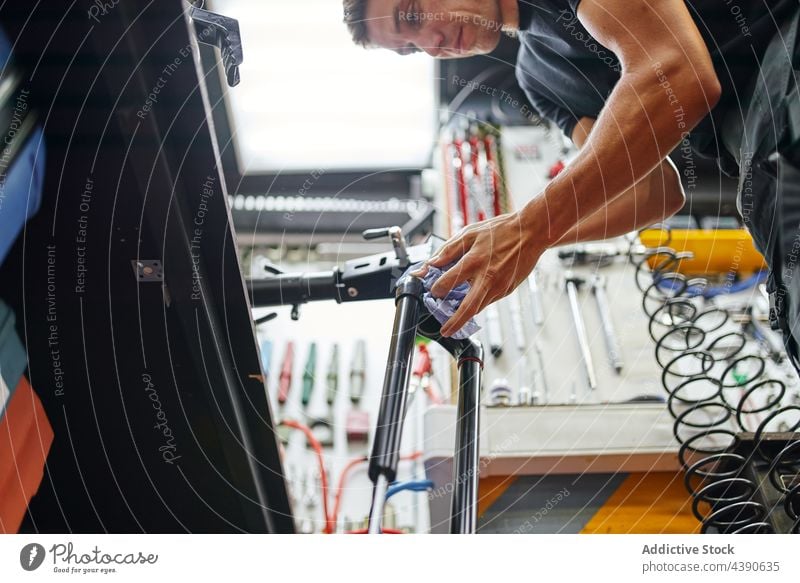 Männlicher Mechaniker beim Abwischen des Fahrradrahmens in der Werkstatt Mann Rahmen Wischen Sauberkeit Dienst übersichtlich männlich Tuch Arbeit Gerät