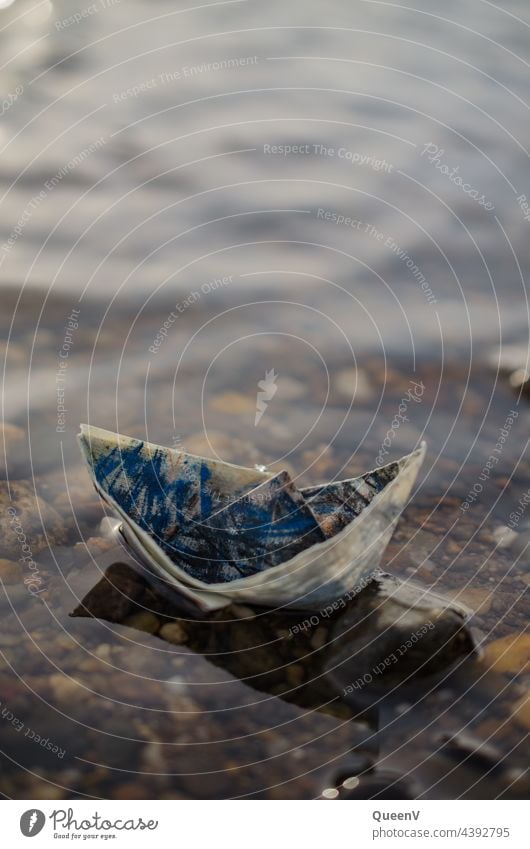 Papierschiff auf Wasser Papierboot Schifffahrt Boot blau reisen Kindheit Kindheitserinnerung navigieren schiffen segeln Urlaub nautisch Freiheit