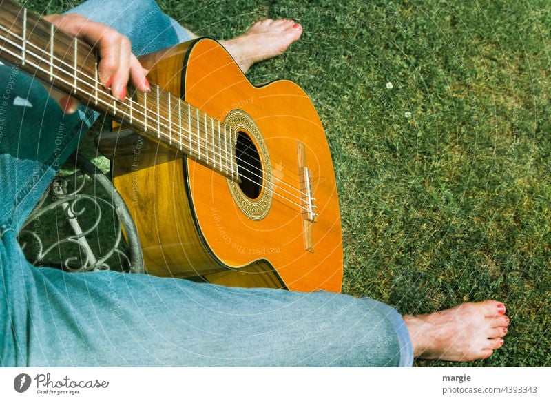 Musik im Park. Gitarrenspielerin spielt auf der Wiese Gitarrensaite Klang Nahaufnahme musizieren Saite Holz Musiker Freizeit & Hobby Barfuß Fuß musikalisch