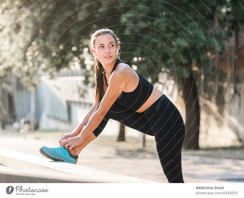 Sportlerin bindet Turnschuhe beim Training Krawatte Schuhbänder Fitness Straße Sommer vorbereiten Pause Frau jung Barriere Athlet Sportbekleidung passen