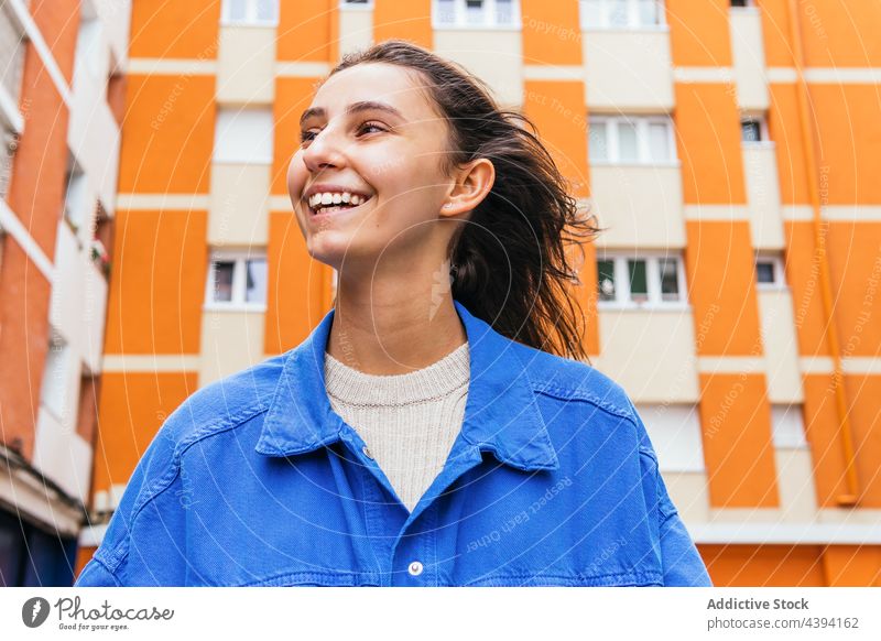 Glückliche Frau steht in der Stadt und lacht Lachen hell Farbe Spaß haben Großstadt urban heiter Straße lebhaft Freude sorgenfrei Stil froh Optimist aufgeregt