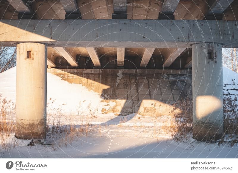 unter der Brücke auf dem zugefrorenen Fluss, Winterabend. Pylone Schnee Röhricht Sonnenuntergang architektonisch urban Wasser Architektur Wahrzeichen reisen