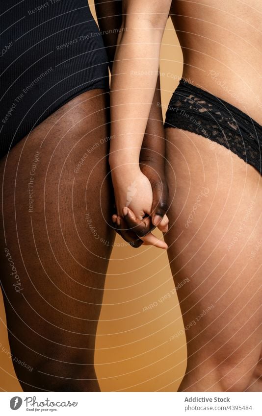 Crop diverse Frauen in Dessous halten Hände körperpositiv Händchenhalten Atelier Unterwäsche akzeptieren Zusammensein Körper Figur vielfältig rassenübergreifend