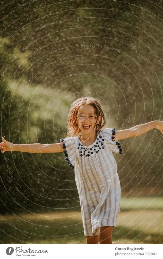 Niedliches kleines Mädchen hat Spaß unter Bewässerung Sprinkler Glück Kind Sommer Fröhlichkeit Freude Sprinkleranlage Spray nass aktiv Wasser im Freien