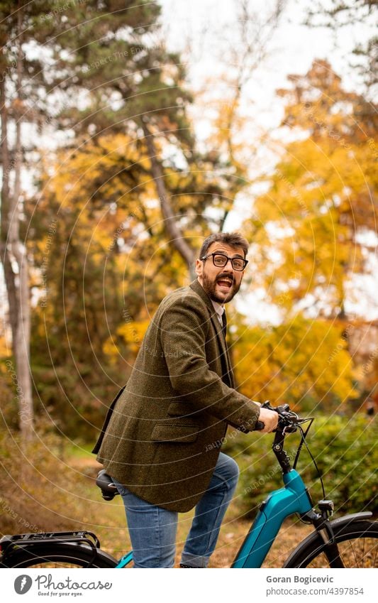 Junger Mann mit Elektrofahrrad im herbstlichen Park Fahrrad jung Natur elektrisch Lifestyle im Freien Aktivität Farbe Zyklus Mitfahrgelegenheit Sommer Tag