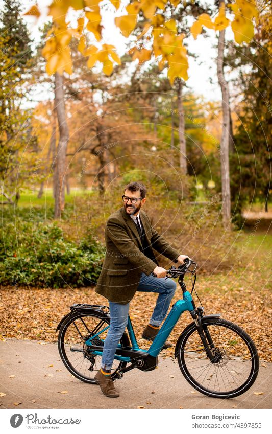 Junger Mann mit Elektrofahrrad im herbstlichen Park Fahrrad jung Natur elektrisch Lifestyle im Freien Aktivität Farbe Zyklus Mitfahrgelegenheit Sommer Tag