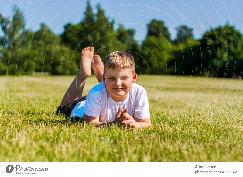 Ein fröhliches Kind lächelt vor Freude. Ich bin glücklich zu gehen und spielen auf dem Rasen in warmen sonnigen Wetter im Park. die Emotionen der Kinder auf dem Gesicht.