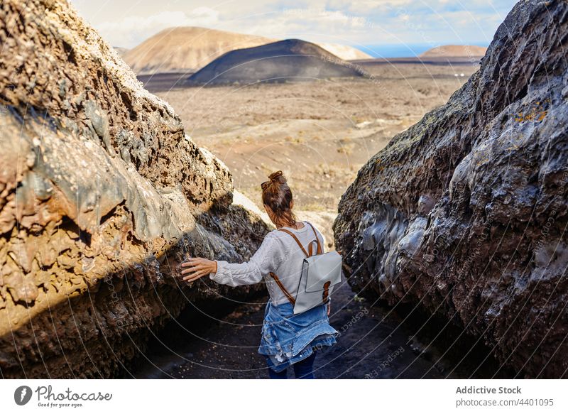 Weiblicher Reisender berührt felsige Oberfläche Frau Spaziergang Hochland berühren Felsen Formation erkunden Ausflug Sommer Wochenende Fuerteventura Spanien