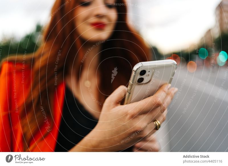 Rothaarige Frau beim Surfen auf dem Smartphone in der Stadt soziale Netzwerke orange Anzug pulsierend Mobile Apparatur Telefon Gerät rote Haare Rotschopf Ingwer