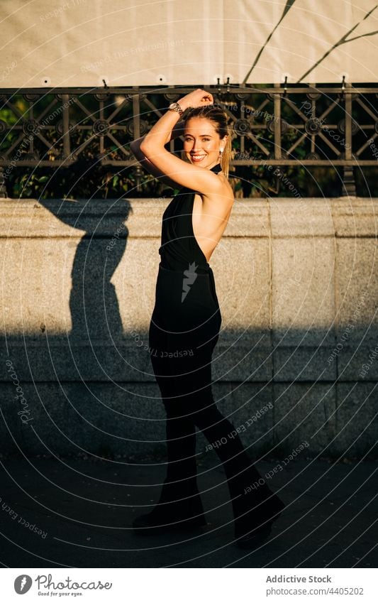 Erfreute stilvolle Frau steht auf der Straße Stil Großstadt trendy Lächeln heiter Sonnenlicht Glück Mode Optimist Freude charmant Sommer Inhalt modern Gebäude