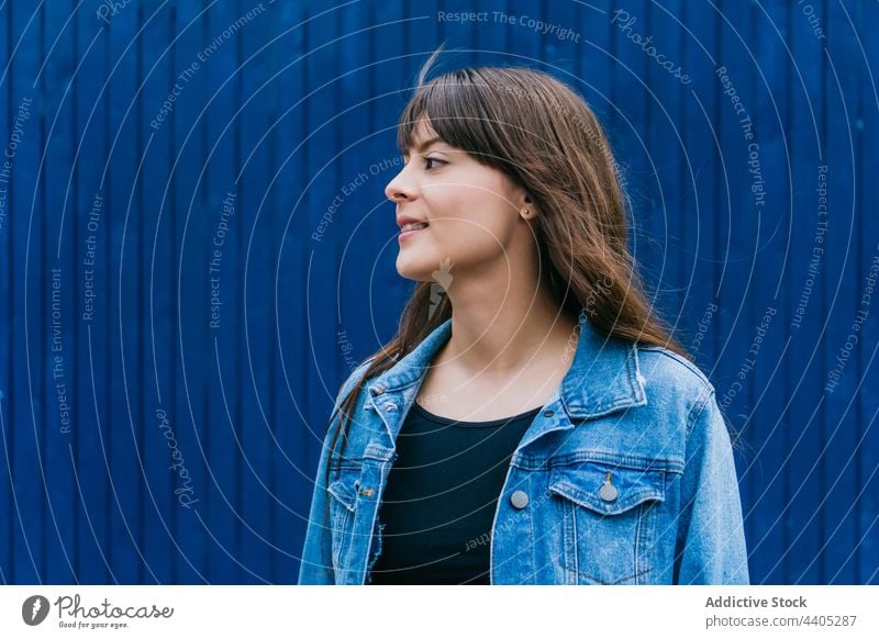 Gelassene Frau mit fliegenden Haaren auf blauem Hintergrund fliegendes Haar lange Haare Gelassenheit Farbe Stil braune Haare ruhig Großstadt urban friedlich