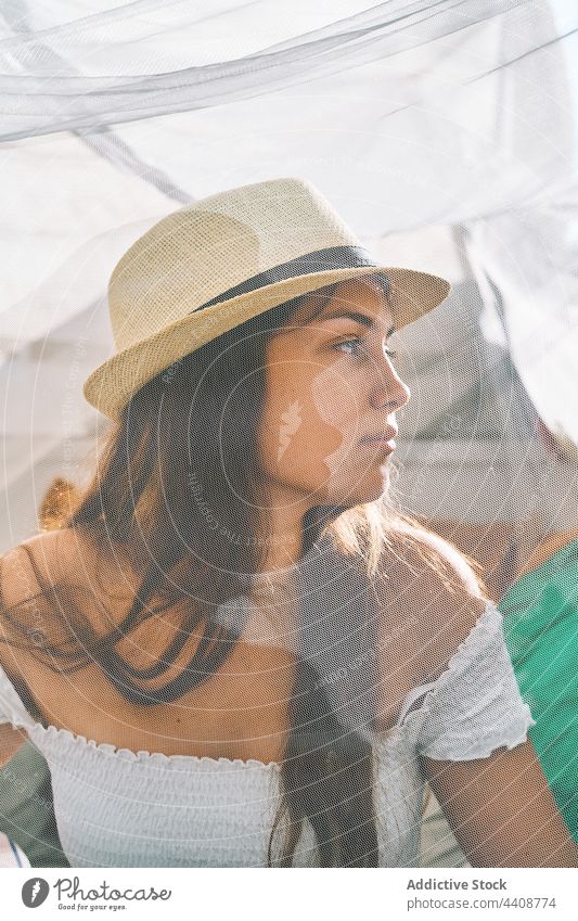 Junge Frau mit Sonnenhut sitzt im Zelt Sommer Inhalt Gardine jung Kälte genießen Hinterhof Lächeln ruhig friedlich durchsichtig Gelassenheit Harmonie