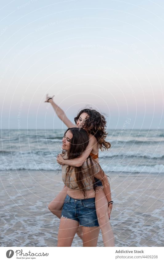 Lesbisches Paar hat Spaß am Meer Frauen Huckepack MEER Abend Freundin Termin & Datum winken lesbisch Zusammensein jung Liebe Strand führen Sommer Wasser