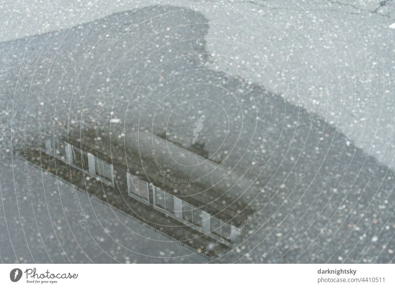 Asphalt mit einer Pfütze voll Wasser und einem sich darin spiegelnden Gebäude. Spiegelung Architektur Stadt freigestellt textfreiraum Fenster Dachgaube Haus