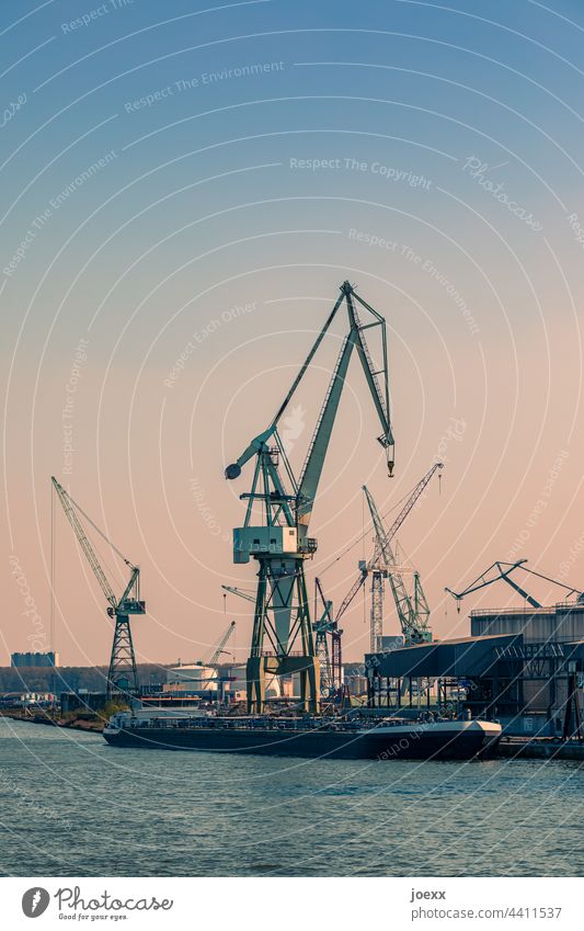 Lastenkräne in Industriehafen am Wasser mit angelegtem Schiff Kran Hafen Kräne Binnenschifffahrt Industrieanlage Flussufer Schönes Wetter Himmel alt