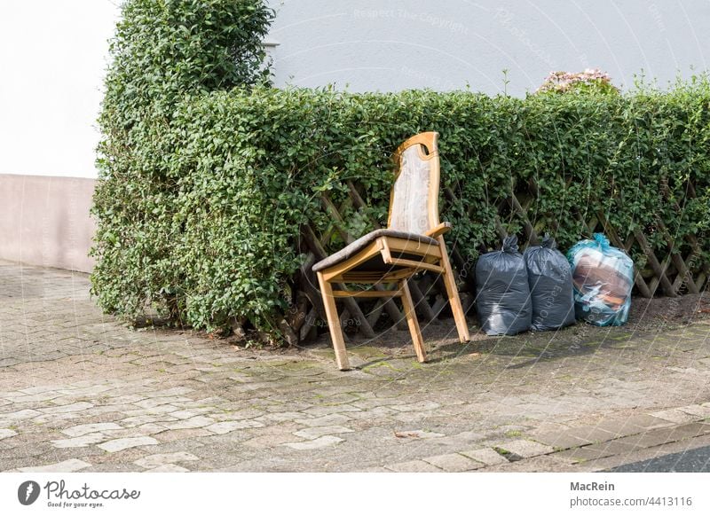 Sperrmüll am Strassenrand aussenaufnahme abfall bürgersteig entsorgen farbfoto hecke holzstuhl kaputt niemand sperrmüll strassenrand stuhlbein zaun